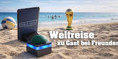Tablet und Buzzer stehen am Strand vor dem Meer, im Hintergrund sind Menschen im Meer, ein Volleyball und der WM Pokal stehen am Strand
